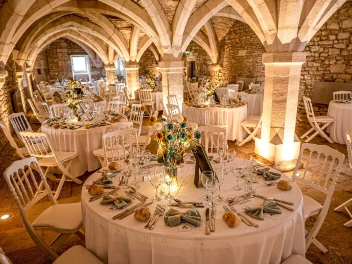 Cave voûtée du château de Riceys-Bas décorée pour un dîner de mariage, tables rondes élégantes, lumière chaleureuse et ambiance intimiste en Champagne.