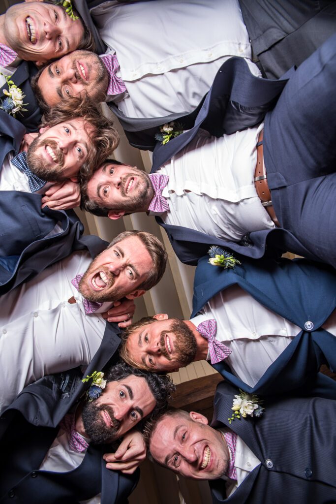 Groupe d’amis du marié réunis tête contre tête, éclats de rire et énergie collective, instant spontané de mariage.