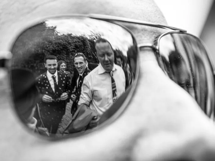 Reflet d’invités dans des lunettes de soleil lors d’un mariage, capturé en noir et blanc pour une photo originale.
