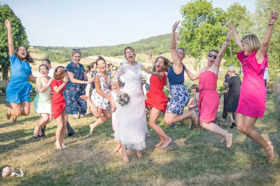 La mariée saute de joie entourée de ses amies lors du vin d’honneur, dans un moment de célébration spontané.
