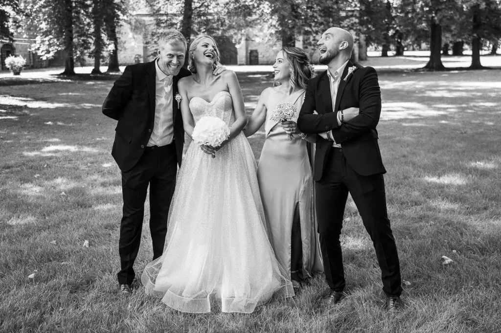 La mariée rit avec ses témoins lors d’un moment de complicité, en noir et blanc.