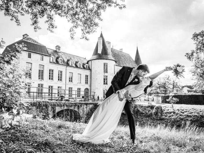Les mariés s’embrassent devant le château de Riceys-Bas, lors d’un mariage dans la champagne, en noir et blanc.