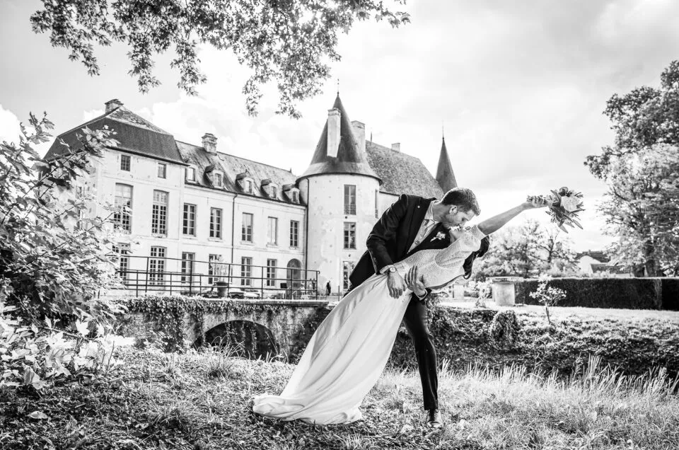 Les mariés s’embrassent devant le château de Riceys-Bas, lors d’un mariage dans la champagne, en noir et blanc.