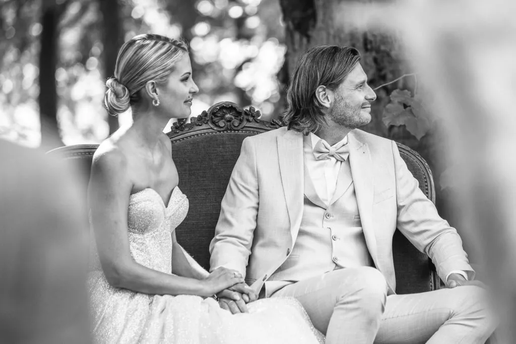 Scène intime et élégante d’un mariage, les mariés assis côte à côte, en noir et blanc.