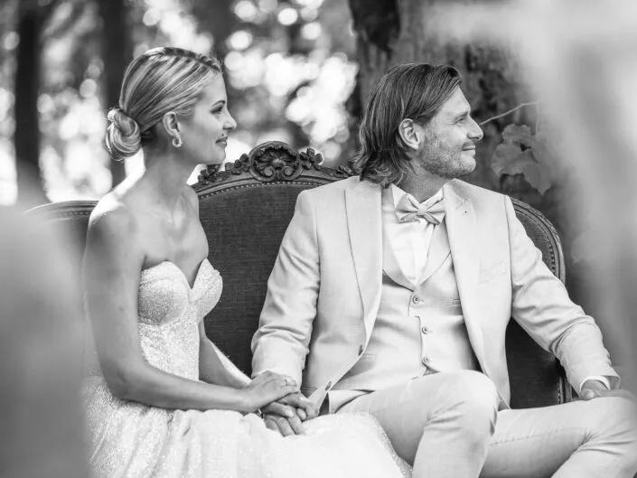 Scène intime et élégante d’un mariage, les mariés assis côte à côte, en noir et blanc.