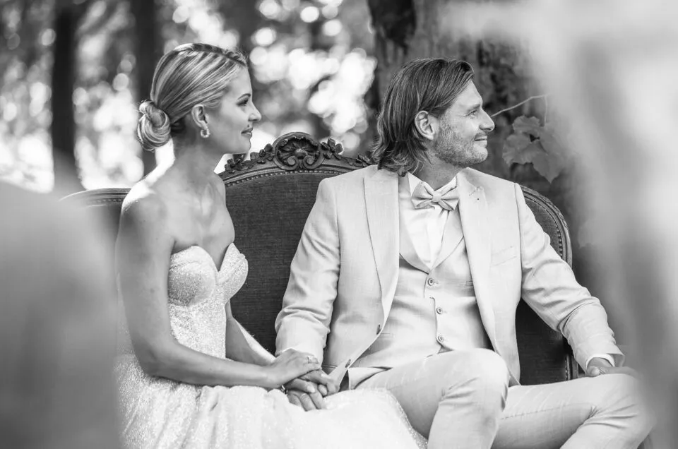 Scène intime et élégante d’un mariage, les mariés assis côte à côte, en noir et blanc.