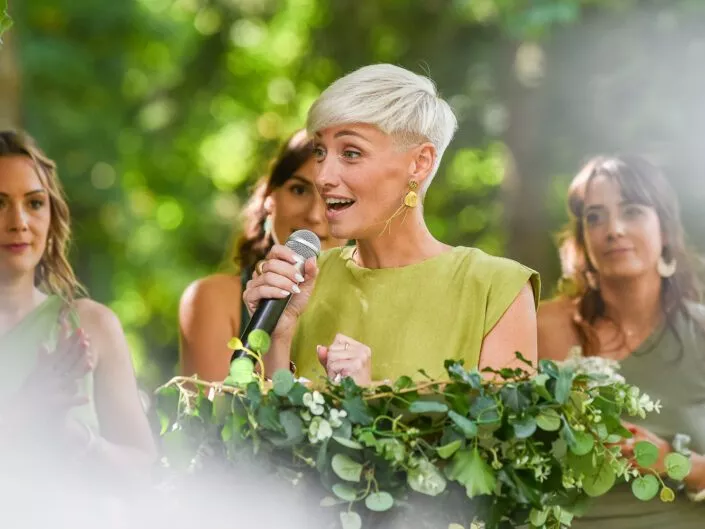 Une demoiselle d’honneur prononce un discours lors d’un mariage en extérieur.