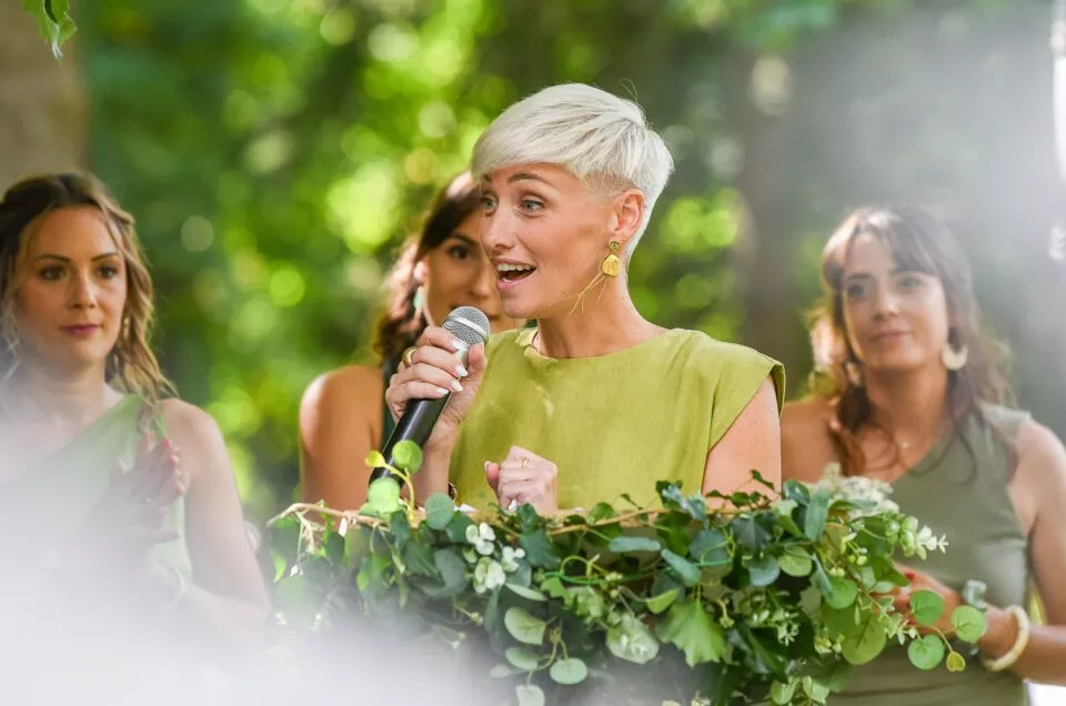 Une demoiselle d’honneur prononce un discours lors d’un mariage en extérieur.