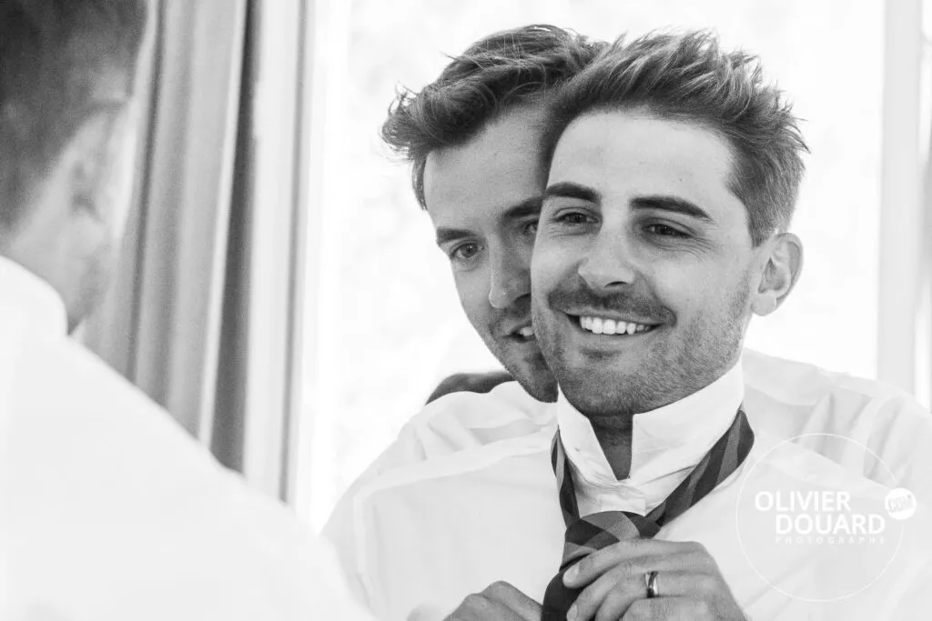 couple souriant pendant les préparatifs de mariage en train d'ajuster la cravate au clos de beaurepaire