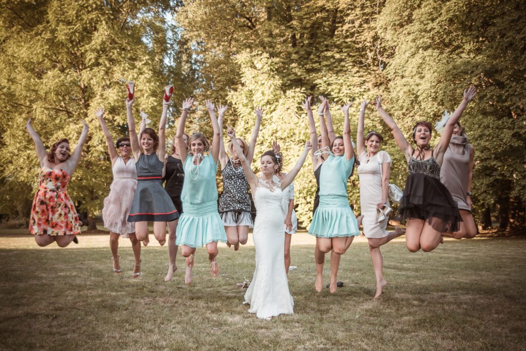 Mariée entourée de ses amies sautant en l’air dans le parc du Domaine de Vauluisant près de Troyes lors d’un reportage photo de mariage.