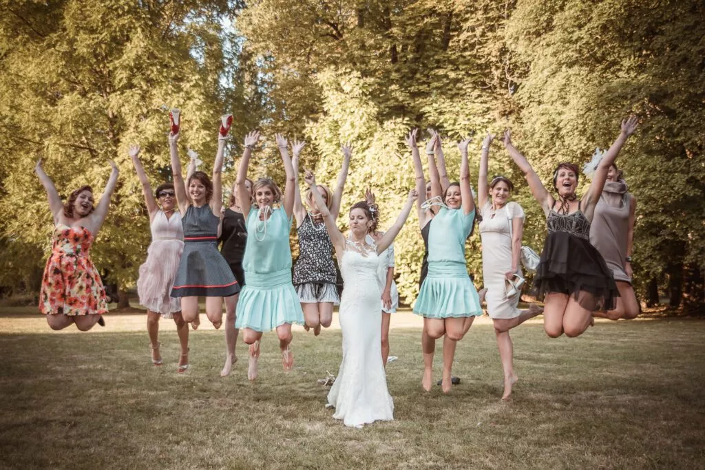 Mariée entourée de ses amies sautant en l’air dans le parc du Domaine de Vauluisant près de Troyes lors d’un reportage photo de mariage.