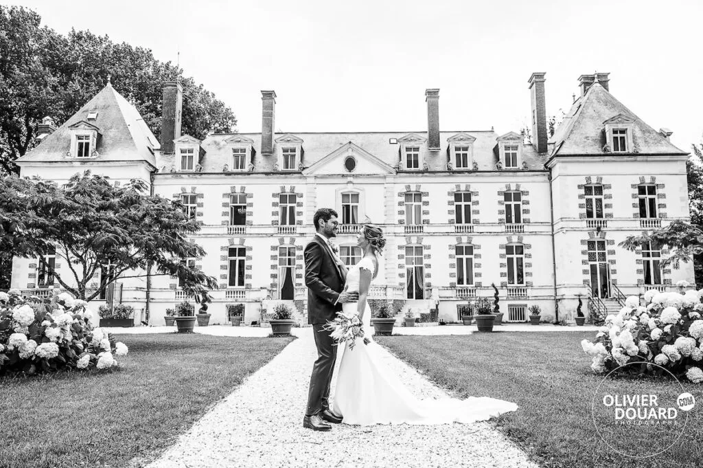 Couple de mariés posant devant le chateau de Percey, photo en noir et blanc