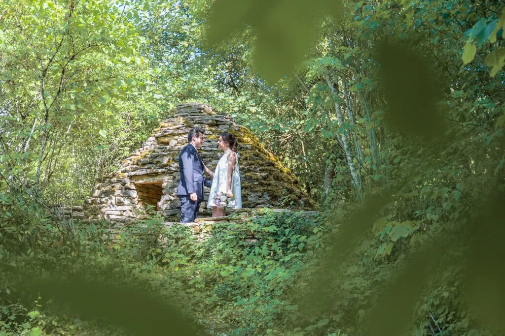 couple qui pose devant une cadole en pierre avec un flou en avant plan