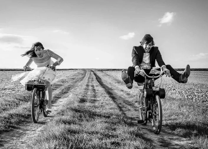 photo en noir et blanc avec des mariés sur des solex tout sourires